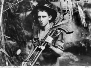 1944-06-22. NEW GUINEA: ANOTHER OF THE "TYPEWRITER TOURISTS" IS PTE A. WUST, OF ROCKHAMPTON, WHO SHOULDERS HIS BREN GUN AS HE SETS OUT ON PATROL IN NORTHERN NEW GUINEA