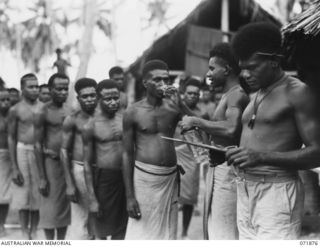 LAE, NEW GUINEA. 1944-03-30. NEW GUINEA NATIVES RECEIVING MEDICINE FROM CORPORAL YASIA (1), AND MEDICAL ORDERLY APEN (2), AT THE AUSTRALIAN NEW GUINEA ADMINISTRATIVE UNIT NATIVE HOSPITAL