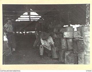 MALAMAL, NEW GUINEA. 1944-07-13. N393309 LIEUTENANT V.C. DIXON (1), QX218 CORPORAL P. MURPHY (2) AND N463974 WARRANT OFFICER II, L. BRIDGER (3) CHECKING SUPPLIES IN THE RATION STORE AT THE ..