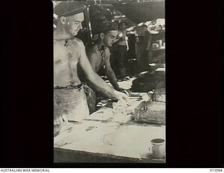 DUGUMUR BAY, NEW GUINEA. 1944-06-14. NX156259 PRIVATE G. C. CAMERON (RIGHT) AND NX131037 LANCE CORPORAL J. W. ANDERSON, MEMBERS OF 4TH INFANTRY BATTALION, CUTTING AND PLACING BREAD ROLLS INTO TINS ..