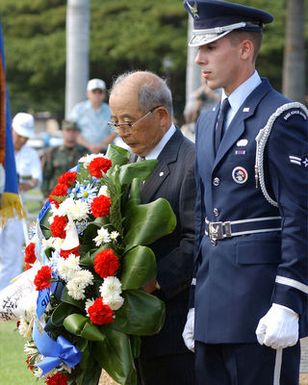 Japanese World War II Veteran Mr. Iwashita, President of the Zero Fighter Pilots Association and US Air Force (USAF) AIRMAN First Class (A1C) Timothy Nichols, a member of the Hickam AFB, Hawaii (HI) Honor Guard Team, pay respects to fallen soldiers during a Flagpole Ceremony held to commemorate the attack on Hickam Field during the Japanese invasion