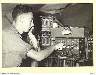 MOTUPINA POINT AREA, BOUGAINVILLE ISLAND. 1945-01-20. VX136038 SIGNALLER A.G. JACOBS OPERATING A 13 LINE SWITCHBOARD IN THE 2ND FIELD REGIMENT SIGNALS SECTION