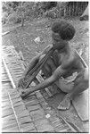 Man sewing thatch panel