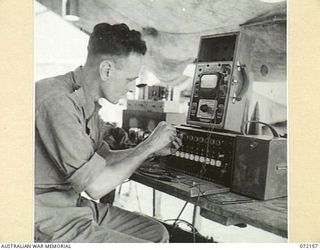 KILIGIA, NEW GUINEA. 1944-04-08. Q126501 SIGNALMAN K.C. GUNN, OF "M" SECTION, 5TH DIVISION SIGNALS, AT HEADQUARTERS 5TH DIVISION WORKING ON A TEN LINE SWITCHBOARD SENT IN FOR MAINTENANCE AND REPAIR ..