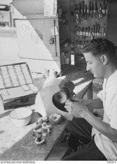 CAPE WOM, WEWAK AREA, NEW GUINEA. 1945-09-01. STAFF SERGEANT G. RIVERS, 2/4 DENTAL UNIT ATTACHED HEADQUARTERS 6 DIVISION POLISHING DENTURES AFTER COMPLETION OF PROCESSING