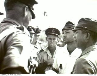 NEW BRITAIN, 1945-09. NEW ZEALAND SERVICE OFFICERS AND JAPANESE LIAISON PERSONNEL TALKING IN THE RABAUL AREA. (RNZAF OFFICIAL PHOTOGRAPH.)