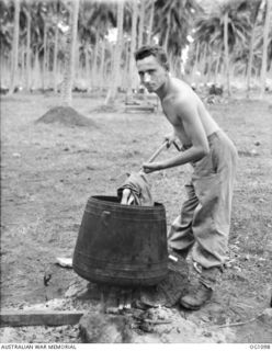 AITAPE, NORTH EAST NEW GUINEA. C. 1944-06. PILOT OFFICER A. MILSTON RAAF OF COOGEE, NSW, USES A JAPANESE COOKING POT FOR WASHING HIS LAUNDRY
