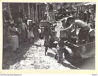 SOUTH BOUGAINVILLE. 1945-07-21. NATIVES LOADING RATIONS INTO TRACTOR TRAIN TRAILERS AT THE DETAIL ISSUING DEPOT, HEADQUARTERS 3 SUPPLY DEPOT COMPANY, WEST OF THE OGORATA RIVER. OWING TO THE HEAVY ..