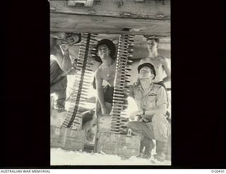 VIVIGANI, GOODENOUGH ISLAND, PAPUA. 1943-12-26. FLYING OFFICER E. ROBINSON OF TORQUAY, QLD (RIGHT), AND NO. 30 (BEAUFIGHTER) SQUADRON RAAF, CHECKING THE ARMOURERS AS THEY LOAD CANNON SHELLS INTO ..