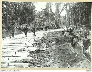 TOKO-BARARA ROAD, BOUGAINVILLE, SOLOMON ISLANDS. 1945-03-28. NATIVES SUPPLIED BY THE AUSTRALIAN NEW GUINEA ADMINISTRATIVE UNIT WORK UNDER THE GUIDANCE OF SAPPERS OF THE 15TH FIELD COMPANY, ROYAL ..