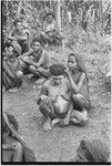 Pregnant woman, face and body smeared with clay (sign of mourning), sits with sister-in-law