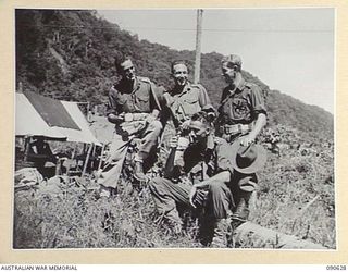 BUT, NEW GUINEA. 1945-04-10. A COMPANY, 2/8 INFANTRY BATTALION OFFICERS ENJOYING A MUG OF TEA AT THEIR CAMP. IDENTIFIED PERSONNEL ARE:- CAPT J.M. GATELY (1); LT G.R. TURNER (2); CAPT E.C. METCALF ..