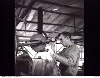 DONADABU, NEW GUINEA. 1943-11-09. NX172089 SAPPER H. H. WHITE, SAW DOCTOR OF THE 9TH AUSTRALIAN WORKSHOP AND PARK COMPANY, ROYAL AUSTRALIAN ENGINEERS SHARPENING A CIRCULAR SAW AT THE EILOGO SAWMILL