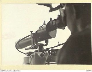 LAE, NEW GUINEA, 1944-03-27. QX54183 GUNNER A. C. FARD ON LOOKING THROUGH THE AZIMUTH INSTRUMENT AT THE OBSERVATION POST AT N HEAVY BATTERY, ROYAL AUSTRALIAN ARTILLERY, ATTACHED TO HEADQUARTERS LAE ..