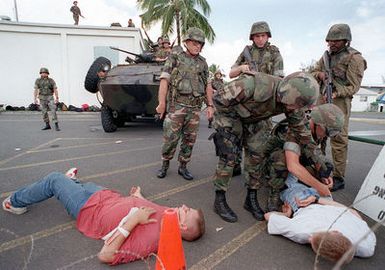 US Marines cover Hospital Corpsman Eric Carver as he searches a wounded civilian during a simulated Noncombatant Evacuation Operation (NEO) at Kaneohe Bay Marine Corps Station, HI. The 11th Marine Expeditionary Unit (MEU) from Camp Pendleton, CA conducted training exercises in the evacuation of civilians from hostile foreign environments, as part of Operation RIMPAC 96