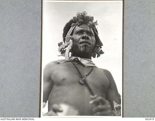 KILA, KILA, PAPUA, NEW GUINEA. 1943-12-25. A NATIVE OF THE MEKEO TRIBE DRESSED FOR THE DANCE WITH FLOWERS IN HIS HAIR AND AN OCHRE PAINTED FACE