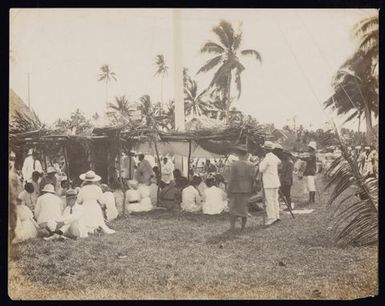 Large group at a ceremony, dining beneath a thatched marquee, Samoa