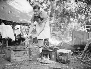 HANSA BAY, NEW GUINEA. 1944-09-06. Q21632 CORPORAL L. BENTLEY, COOK, HEADQUARTERS, 25TH INFANTRY BATTALION PREPARING A MEAL FOR THE TROOPS