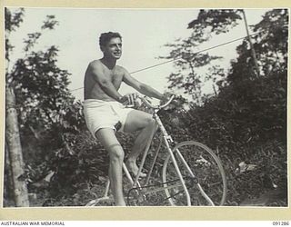 BOUGAINVILLE. 1945-04-26. PRIVATE G.D. BESGROVE, A PATIENT AT 2/3 CONVALESCENT DEPOT, PEDALS A BICYCLE AS PART OF HIS TREATMENT FOR A LEG WOUND