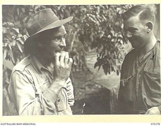 DUMPU, RAMU VALLEY, NEW GUINEA. 1944-02-11. VX84574 WARRANT OFFICER I, R.A.H. MILLARD (1); REGIMENTAL SERGEANT MAJOR, 57/60TH INFANTRY BATTALION SAMPLING A FRITTER MADE BY THE COOKS OF "B" COMPANY. ..