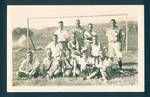 Group portrait of European men and a dog, in front of goal pole, mountain ranges in background, New Guinea, c1929 to 1932