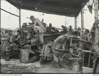 NADZAB, NEW GUINEA. C. 1944-02. MECHANICS OF NO. 62 MOBILE WORKS SQUADRON RAAF IN AN OUTDOOR MOBILE WORKSHOP REPAIRING BULLDOZERS. LEFT TO RIGHT: LEADING AIRCRAFTMAN (LAC) J. W. FLANNAGAN, KYOGLE, ..