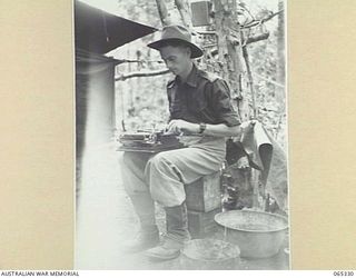 KILIGIA, NEW GUINEA. 1944-03-20. SX23588 SERGEANT THOMAS HENRY FARRELL OF THE AUSTRALIAN PUBLIC RELATIONS FIELD UNIT, USING A TYPEWRITER ON HIS LAP