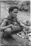 Man kneeling on ground with hand full of kofu shell money