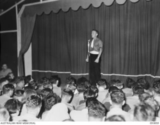 LAE AREA, NEW GUINEA, 1945-07-09. SIGNALMAN F.D. FUERY, 19 LINES OF COMMUNICATION AREA SIGNALS SINGING THE OPENING NUMBER OF THE REVUE "OVER TO YOU" STAGED BY 19 LINES OF COMMUNICATION AREA ..