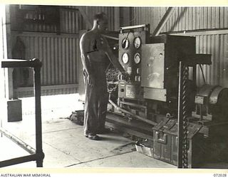 MILNE BAY, NEW GUINEA. 1944-04-04. NX170965 STAFF-SERGEANT S.W. LYME (1), 5TH ARMY TROOP COMPANY, ROYAL AUSTRALIAN ENGINEERS, CHECKS THE FREQUENCY METER OF A FORD GENERATOR SET AT THE MILNE BAY ..