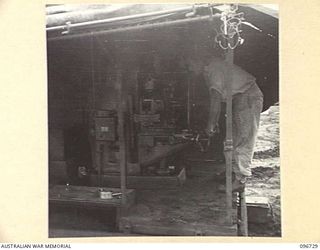 MOEM, WEWAK AREA, NEW GUINEA, 1945-09-17. CRAFTSMAN R.F. PHILLIPS, 2/4 ARMOURED REGIMENT DETACHMENT WITH 4 INFANTRY TROOPS WORKSHOP, WORKING ON A LATHE