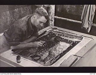 SEVENTEEN MILE, NEW GUINEA. 1943-09-23. NX143647 LANCE CORPORAL A. V. JOHNSON, LITHO ARTIST OF THE 2/1ST AUSTRALIAN ARMY TOPOGRAPHICAL SURVEY COMPANY, "DUFFING OUT" NEGATIVES WHICH WILL ULTIMATELY ..