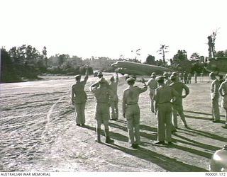 THE SOLOMON ISLANDS, 1945. US AND ALLIED OFFICERS WAVE FAREWELL AS AMERICAN MAJOR GENERAL R.J. MITCHELL'S C47 AIRCRAFT MOVES OUT FOR TAKEOFF ON THE GENERAL'S DEPARTURE FROM BOUGAINVILLE ISLAND