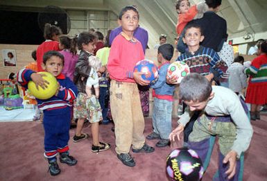 Kurdish children excitedly look through toys upon their arrival at Andersen Air Force Base, Guam, following an almost 17 hour flight from Turkey. The toys were provided for the children through donations by the Salvation Army Guam Corps, the American Red Cross, the Navy/Marine Corps Relief Society, various religious charities and military and civilian private donors. Operation PACIFIC HAVEN represents a series of airlifts designed to provide sanctuary for some 2,400 refugees fleeing Iraq. Many are considered traitors by the Iraqi Government for working with the CIA-funded Iraqi National Congress and international humanitarian agencies. The Kurds will be housed at Andersen AFB, while they...