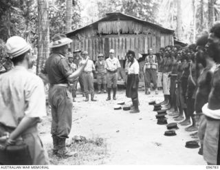 BONIS PENINSULA, BOUGAINVILLE, 1945-09-19. CAPTAIN C. SLATTERY, AUSTRALIAN NEW GUINEA ADMINISTRATIVE UNIT REPRESENTATIVE WITH THE AUSTRALIAN SURRENDER PARTY FROM HQ 2 CORPS, ADDRESSING NATIVE ..