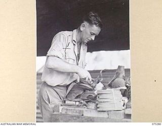 MADANG, NEW GUINEA. 1944-08-15. NX191544 CORPORAL A.E. MCINNES, BOOTMAKER, 165TH GENERAL TRANSPORT COMPANY, ENGAGED HALFSOLING A PAIR OF BOOTS