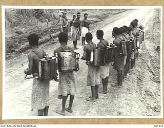 DUMPU, NEW GUINEA. 1943-12-06. QX54520 CORPORAL D. B. ABERDEEN OF THE 18TH AUSTRALIAN ANTI-MALARIAL CONTROL UNIT GIVING INSTRUCTIONS TO A TEAM OF NATIVE BOYS BEFORE THEY SET OUT TO SPRAY THE ..