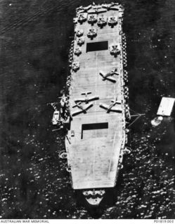 Noumea, New Caledonia, 1943-01-20. The United States Navy (USN) Escort Aircraft Carrier USS Chenango (CV-28) at anchor off Noumea. Aircraft on the flight desk include seven Douglas SBD Dauntless, ..
