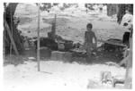 Child standing in yard, pig foraging in pot