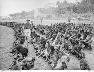 KIARIVU, NEW GUINEA, 1945-08-17. CAPTAIN R.R. COLE, ASSISTANT DISTRICT OFFICER, AUSTRALIAN NEW GUINEA ADMINISTRATIVE UNIT, MAPRIK, NEW GUINEA, AT THE AIRSTRIP COUNTING SOME OF THE 1150 REFUGEE ..