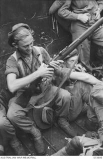 SARANG HARBOUR, NEW GUINEA. 1944-05-31. VX141576 PRIVATE J. PATTISON (1), 37/52ND INFANTRY BATTALION, LOADS HIS RIFLE IN A LANDING BARGE DURING FINAL PREPARATIONS FOR THE ATTACK ON KARKAR ISLAND