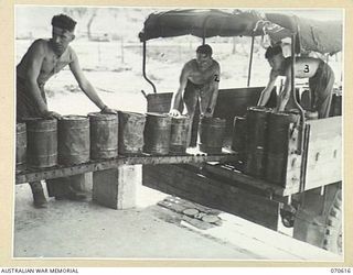 PORT MORESBY, PAPUA. 1944-02-25. PERSONNEL LOADING 4 GALLON DRUMS ON A VEHICLE AT THE CAN FILLING PLANT, 1ST PETROLEUM STORAGE COMPANY. IDENTIFIED PERSONNEL ARE:- VX109776 DRIVER D. GINNIVAN, 126 ..