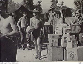 MALMAL VILLAGE, NEW BRITAIN. 1944-12-24. AUSTRALIAN COMFORTS FUND CHRISTMAS HAMPERS BEING DISTRIBUTED AT HEADQUARTERS, 5TH DIVISION. IDENTIFIED PERSONNEL ARE: CRAFTSMAN J. ILLINGWORTH (1); PRIVATE ..