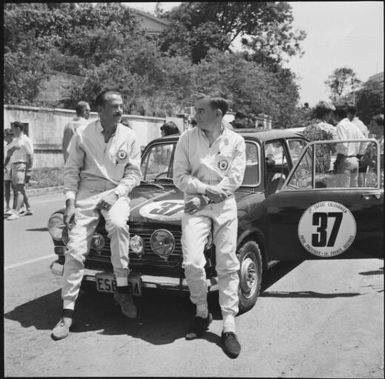 Two rally drivers leaning on their rally car during the 1st Safari Calédonien racing event, New Caledonia, 1967 / Michael Terry