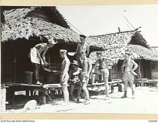 PAPUA, NEW GUINEA. 1942-08. YOUTHFUL AUSTRALIAN SOLDIERS MANNING A FORWARD POST IN NEW GUINEA HAVE TAKEN UP RESIDENCE IN A DESERTED NATIVE VILLAGE. HERE THEY ARE SEEN LINING UP FOR A MEAL
