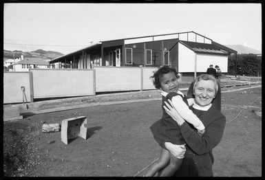 Sister Veronica holding a child in front of the new Polynesian Centre in Porirua