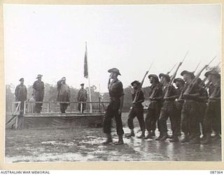 HERBERTON, QUEENSLAND. 1945-03-03. MAJOR GENERAL G.F. WOOTTEN, GENERAL OFFICER COMMANDING 9 DIVISION, (1), TAKING THE SALUTE DURING THE MARCH PAST FROM HEADQUARTERS 24 INFANTRY BRIGADE TROOPS. THE ..