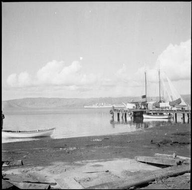Beached rowboat and a jetty with moored ships and HMAS Australia [?] , Rabaul Harbour, New Guinea, 1937 / Sarah Chinnery