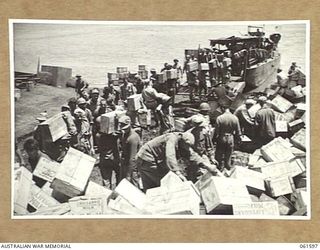 FINSCHHAFEN, NEW GUINEA. 1943-11-20. LOADING STORES AND EQUIPMENT ONTO BARGES AT THE BEACHHEAD