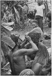 Pig festival, wig ritual: man applies hot tree resin to wig